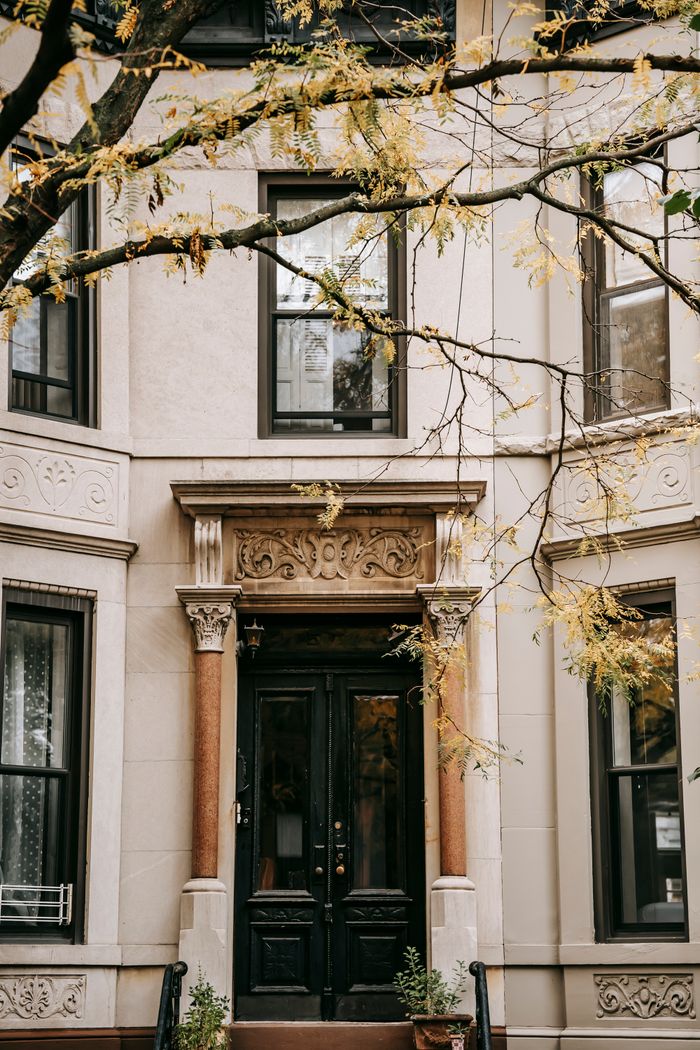Facade of aged residential building with ornamental walls and black wooden door with columns placed in city in daylight